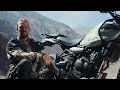 Himalayan 411 Motorcycle parked beside man, mountainous terrain in background, sunny day.