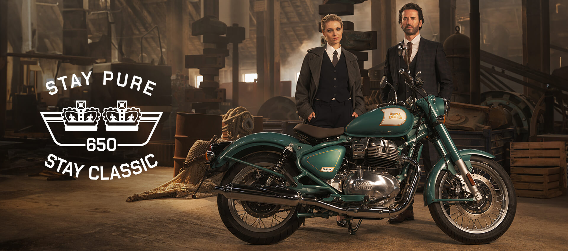 Royal Enfield Classic 650 Motorcycle displayed in a vintage workshop setting, accompanied by two people. Text: "STAY PURE, 650, STAY CLASSIC."